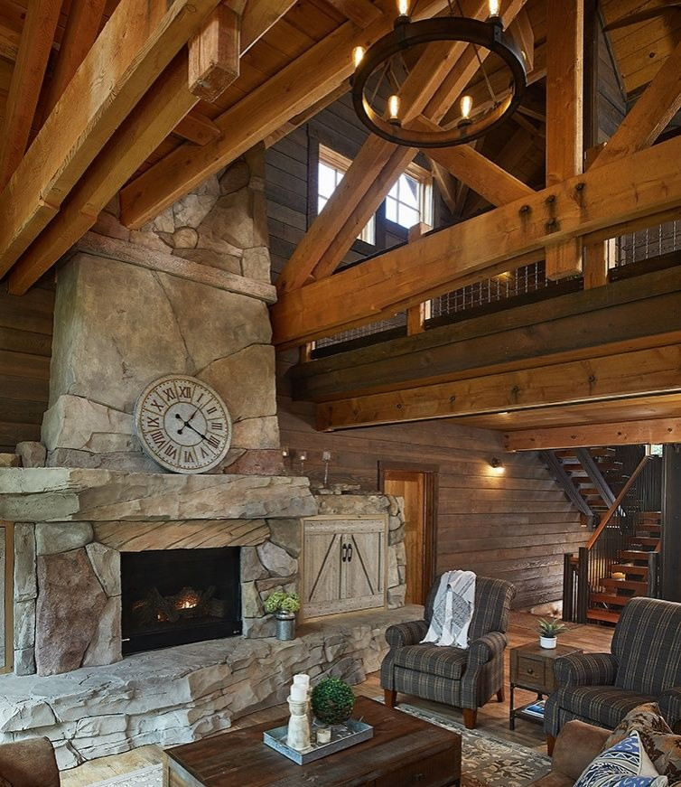 Imagen de sala de estar abierta rústica con suelo de madera clara, estufa de leña y marco de chimenea de piedra