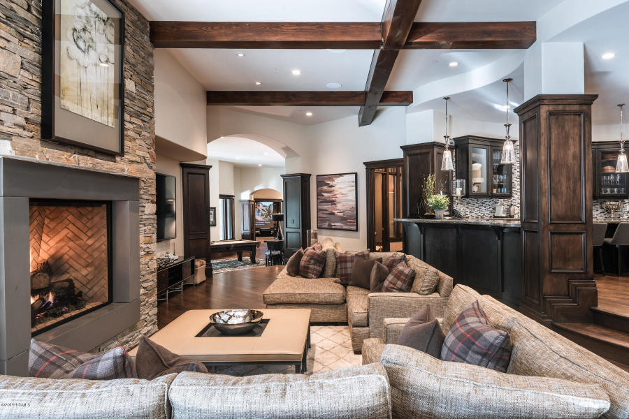 Photo of a large traditional open plan games room in Salt Lake City with a home bar, grey walls, dark hardwood flooring, a standard fireplace, a stone fireplace surround, a wall mounted tv and brown floors.