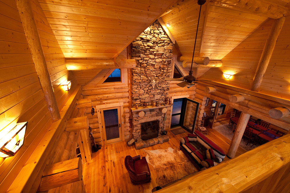 Ejemplo de sala de estar abierta rural pequeña con suelo de madera clara, todas las chimeneas y marco de chimenea de piedra