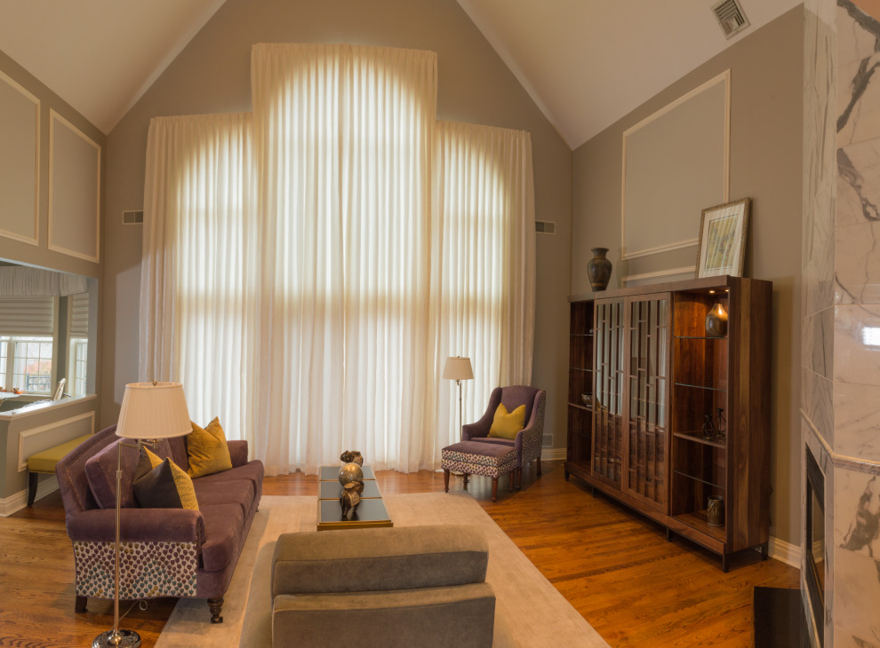Cette image montre une grande salle de séjour traditionnelle ouverte avec un sol en bois brun, une cheminée d'angle, un manteau de cheminée en pierre, un téléviseur dissimulé, un mur gris et un sol marron.