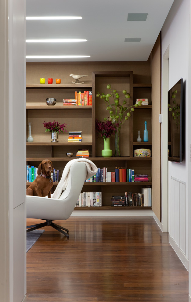 Foto di un soggiorno design con libreria, pareti beige e parquet scuro