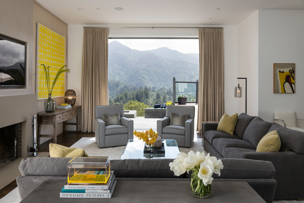 Imagen de sala de estar abierta contemporánea de tamaño medio con todas las chimeneas, televisor colgado en la pared, paredes grises y marco de chimenea de yeso