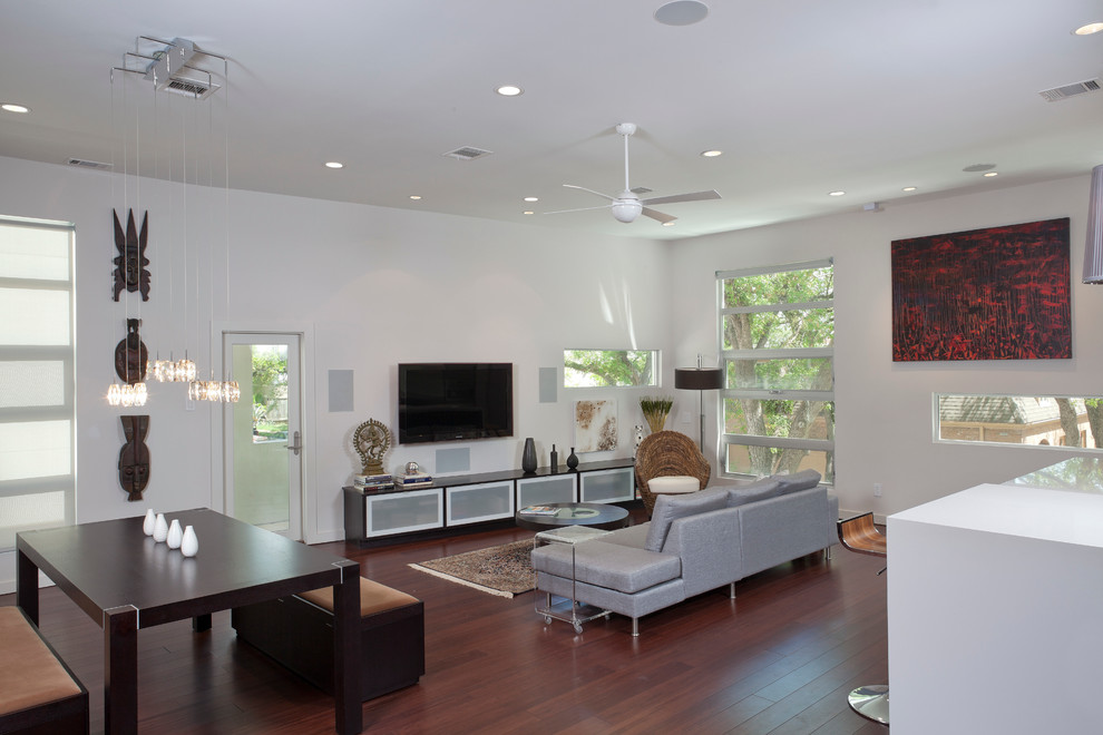 Modelo de sala de estar abierta actual con paredes blancas, suelo de madera oscura y televisor colgado en la pared