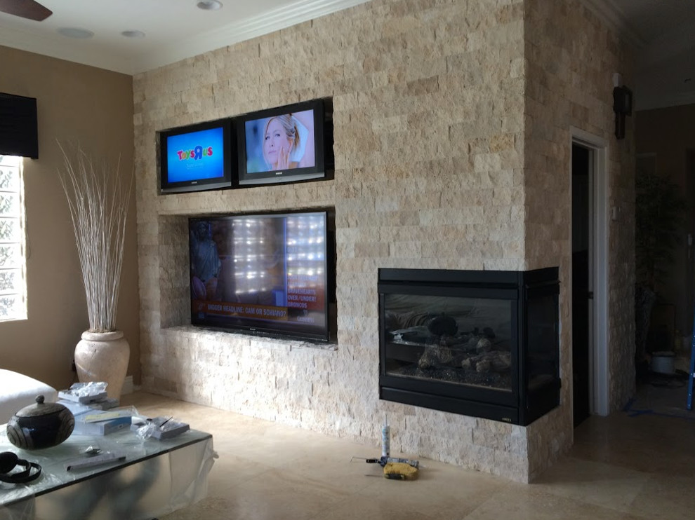 ラスベガスにある高級な中くらいなトランジショナルスタイルのおしゃれな独立型ファミリールーム (ベージュの壁、ライムストーンの床、コーナー設置型暖炉、石材の暖炉まわり、壁掛け型テレビ、ベージュの床) の写真