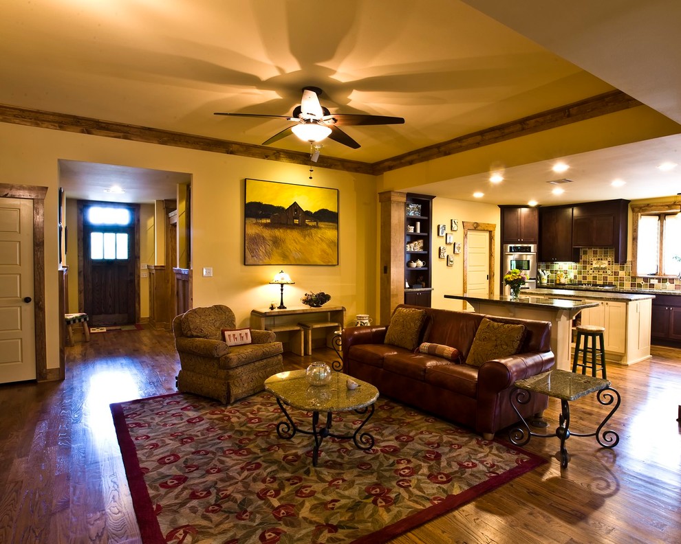 Idee per un soggiorno american style di medie dimensioni e aperto con pareti gialle, pavimento in legno massello medio, nessuna TV, nessun camino e pavimento marrone