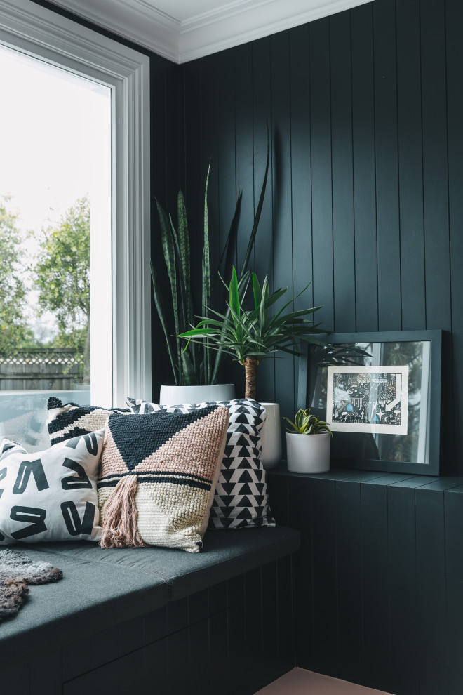 Imagen de sala de estar contemporánea con paredes negras, suelo de madera pintada, estufa de leña, marco de chimenea de metal, suelo rosa y boiserie