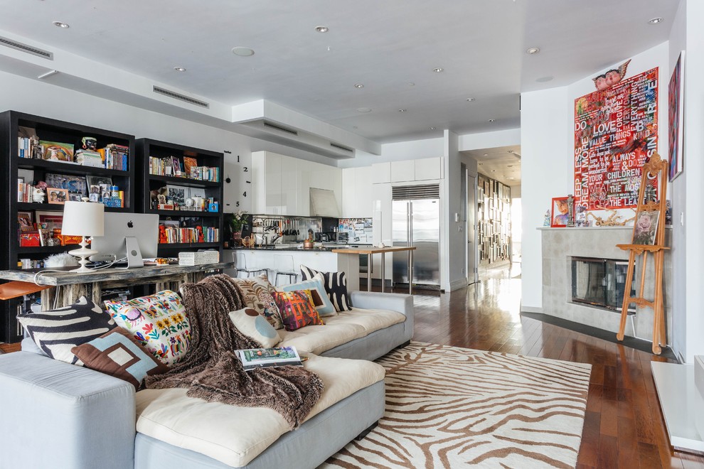 Eclectic open plan games room in New York with white walls, medium hardwood flooring, a corner fireplace, a concrete fireplace surround and no tv.