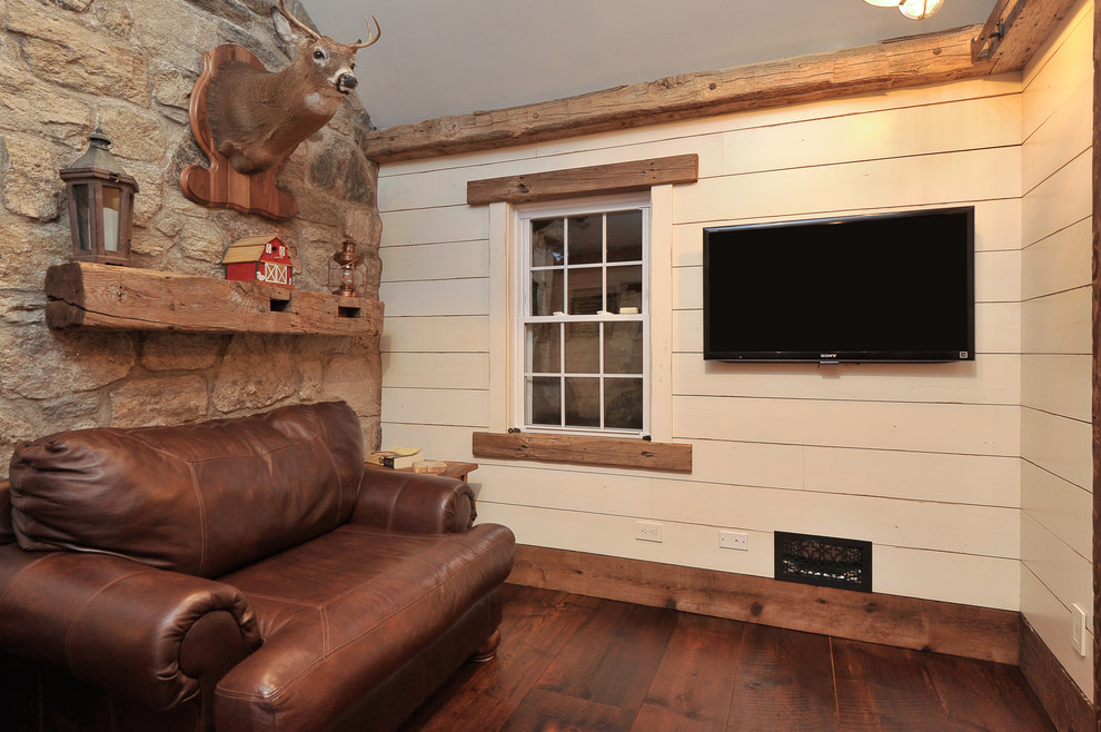 Ejemplo de sala de estar cerrada rústica de tamaño medio con paredes beige, suelo de madera oscura y televisor colgado en la pared