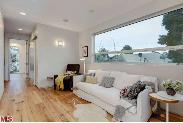Esempio di un piccolo soggiorno minimalista aperto con pareti bianche, parquet chiaro e TV a parete