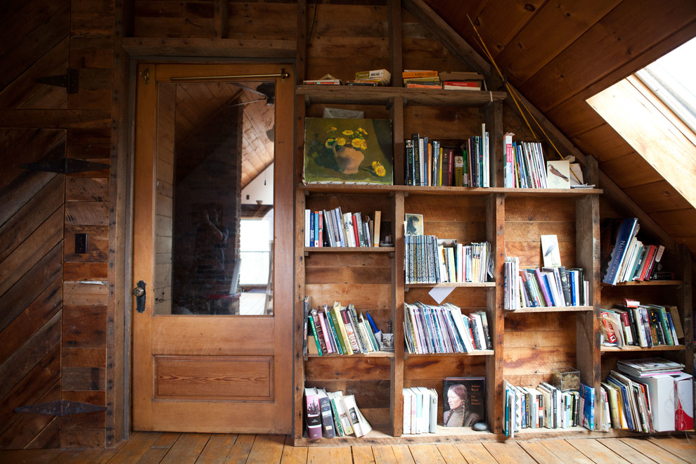 Réalisation d'une salle de séjour champêtre fermée avec une bibliothèque ou un coin lecture, un mur marron et un sol en bois brun.