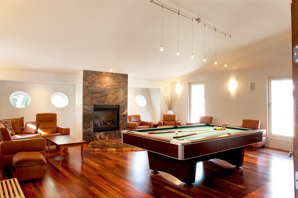 Contemporary open plan games room in Boston with beige walls, dark hardwood flooring and a standard fireplace.
