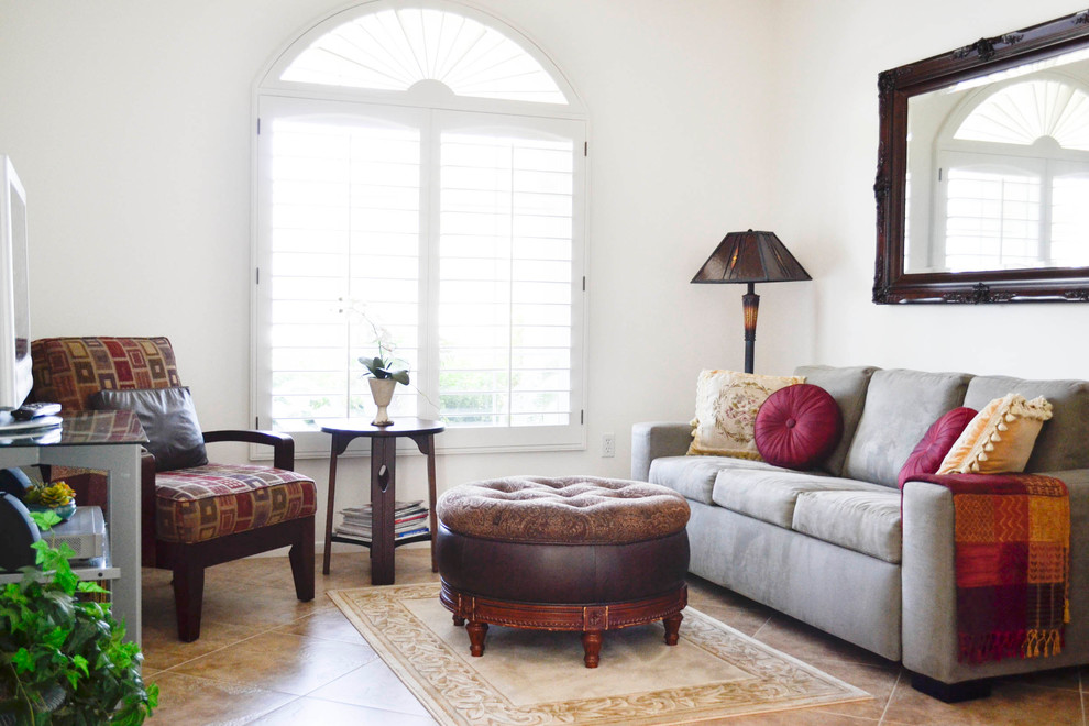 Example of a small tuscan enclosed travertine floor family room design in Los Angeles with a tv stand and white walls