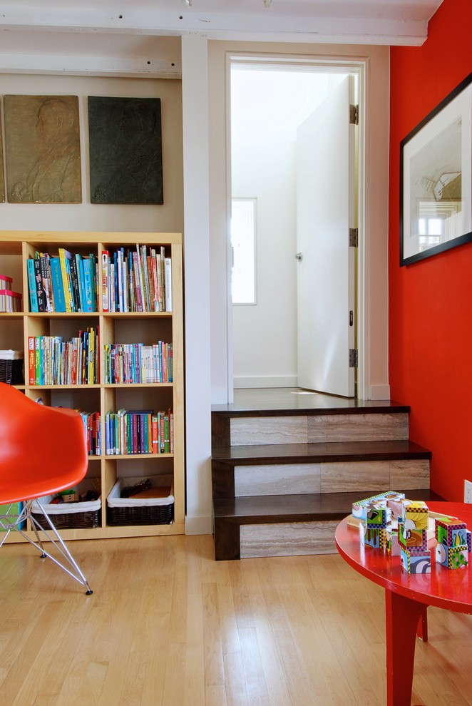 Ispirazione per un soggiorno chic con libreria, pareti arancioni e pavimento in legno massello medio