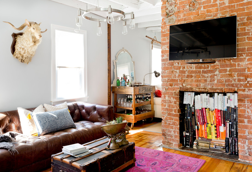 Example of an eclectic medium tone wood floor family room design in Providence with a bar, white walls and a wall-mounted tv