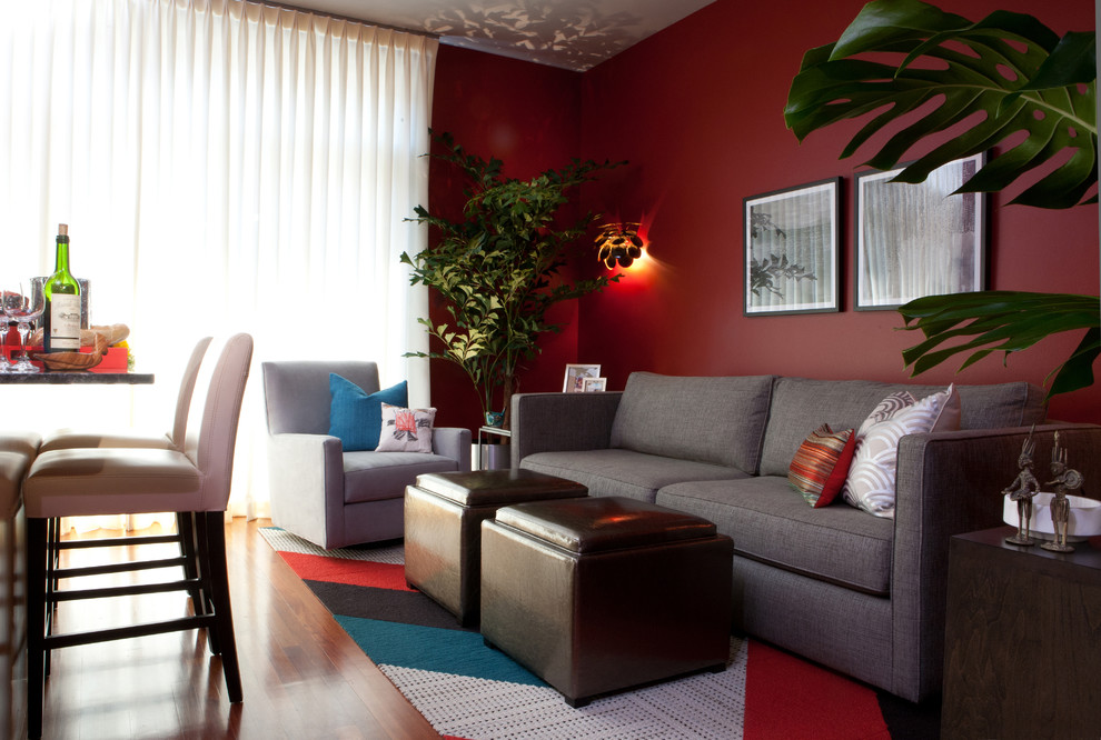 Ispirazione per un piccolo soggiorno design aperto con pareti rosse, pavimento in legno massello medio, nessun camino e TV a parete