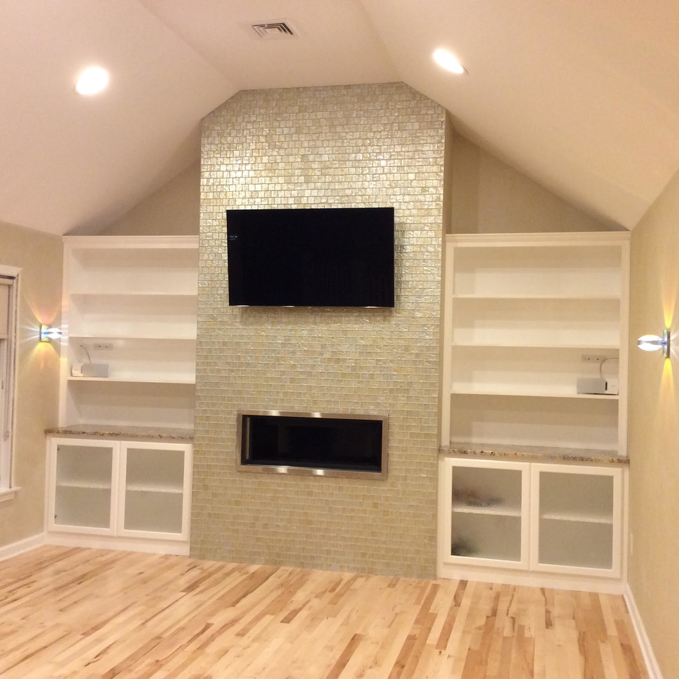 Idée de décoration pour une grande salle de séjour minimaliste fermée avec un mur beige, parquet clair, un manteau de cheminée en carrelage et un téléviseur fixé au mur.