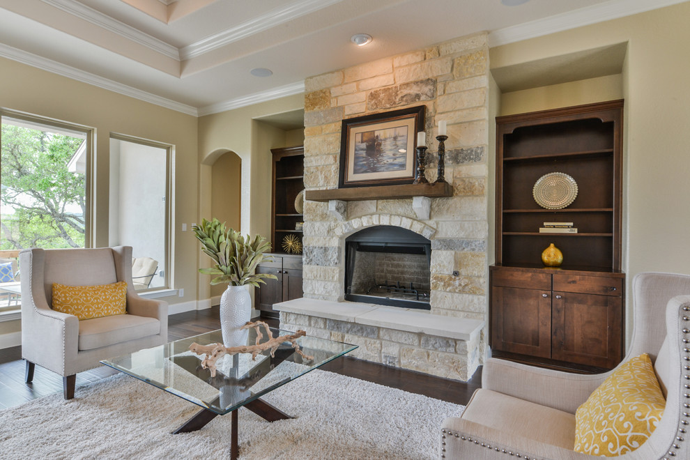 Medium sized traditional open plan games room in Austin with beige walls, dark hardwood flooring, a standard fireplace, a stone fireplace surround, a wall mounted tv and brown floors.