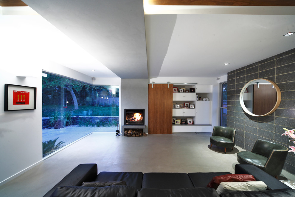 キャンベラにある高級な広いコンテンポラリースタイルのおしゃれなオープンリビング (コンクリートの床、標準型暖炉、漆喰の暖炉まわり、内蔵型テレビ) の写真