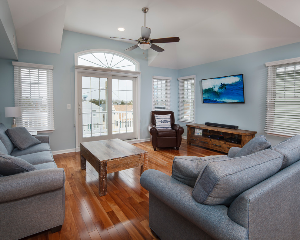 Esempio di un soggiorno costiero di medie dimensioni e aperto con pareti blu, pavimento in legno massello medio e TV a parete