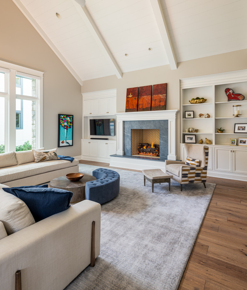Klassisches Wohnzimmer mit beiger Wandfarbe, braunem Holzboden, Kamin, Kaminumrandung aus Stein, Multimediawand und braunem Boden in Nashville