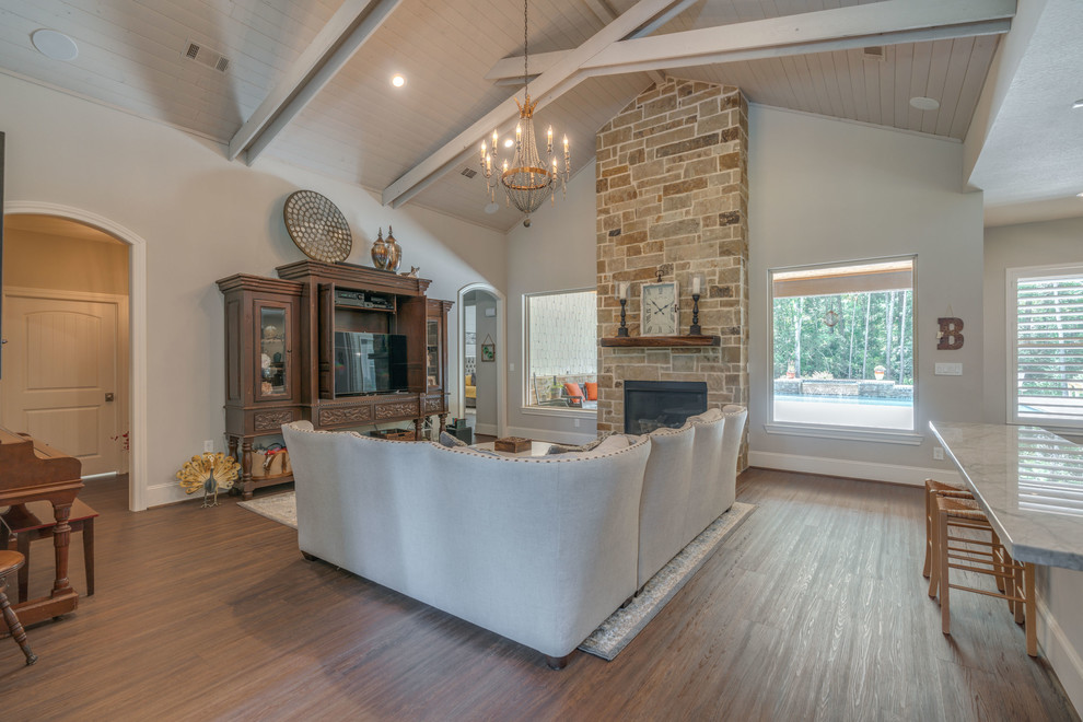 Large eclectic open concept vinyl floor and brown floor family room photo in Houston with gray walls, a standard fireplace, a stone fireplace and a tv stand