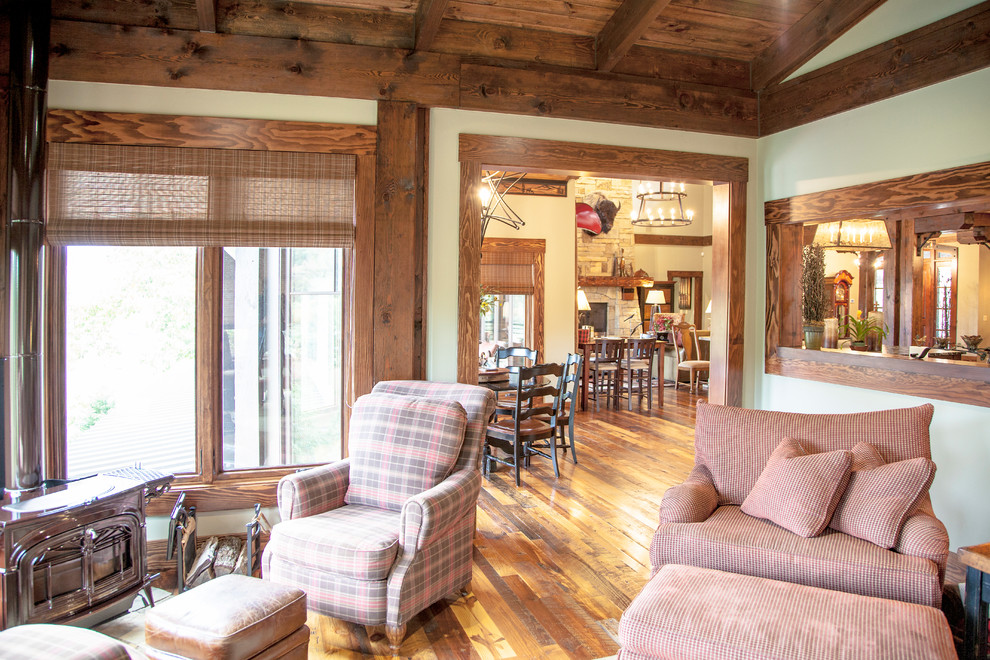Imagen de sala de estar cerrada rústica grande con paredes beige, suelo de madera en tonos medios, estufa de leña y suelo marrón