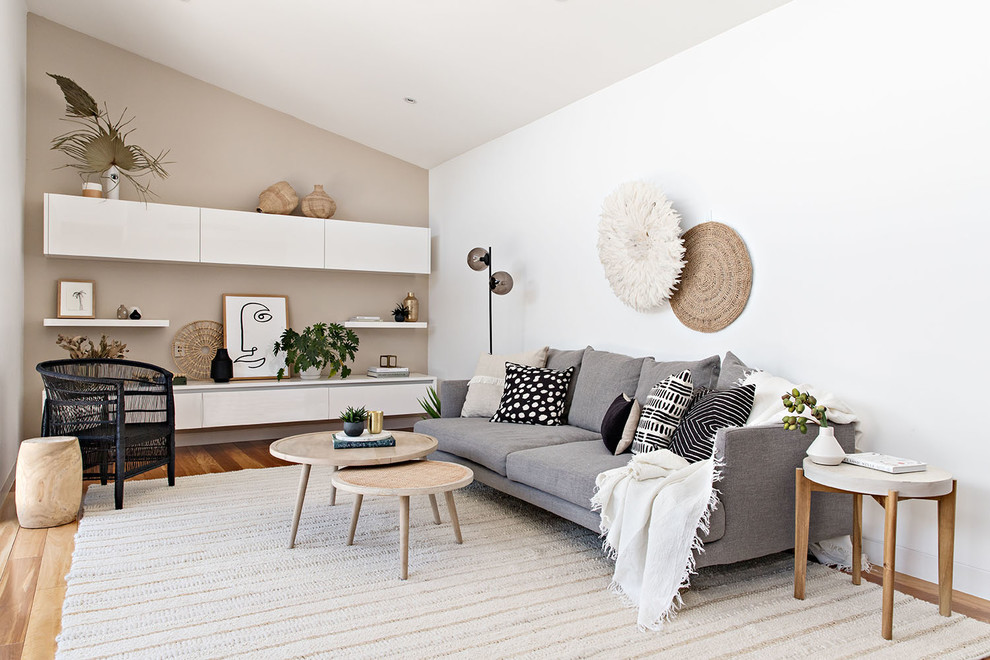 Modelo de sala de estar abierta marinera de tamaño medio sin chimenea y televisor con paredes blancas, suelo de madera en tonos medios y suelo marrón