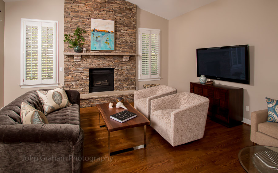 Diseño de sala de estar contemporánea de tamaño medio con paredes beige, suelo de madera en tonos medios, todas las chimeneas, marco de chimenea de piedra y televisor colgado en la pared
