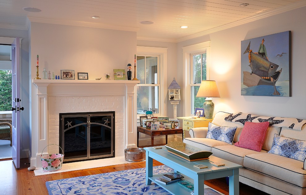 Modelo de sala de estar marinera con paredes azules, suelo de madera clara, todas las chimeneas y marco de chimenea de madera
