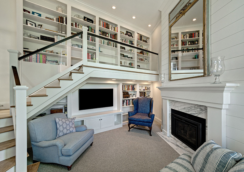 Cette image montre une petite salle de séjour marine avec une bibliothèque ou un coin lecture, moquette, une cheminée standard, un manteau de cheminée en pierre, un téléviseur encastré, un mur blanc et un sol gris.