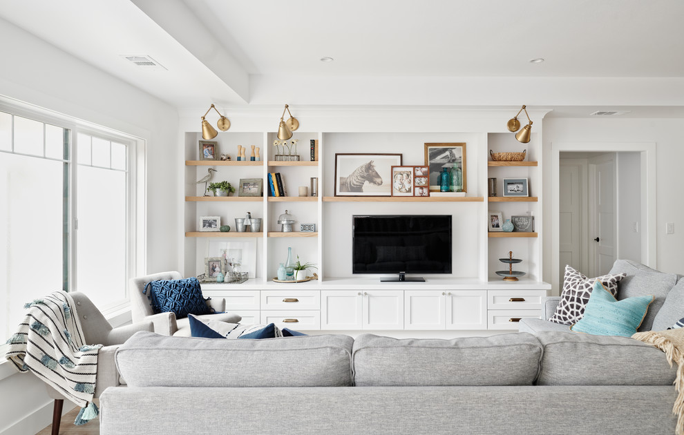 Example of a large beach style open concept light wood floor and brown floor family room design in San Francisco with white walls, no fireplace and a media wall