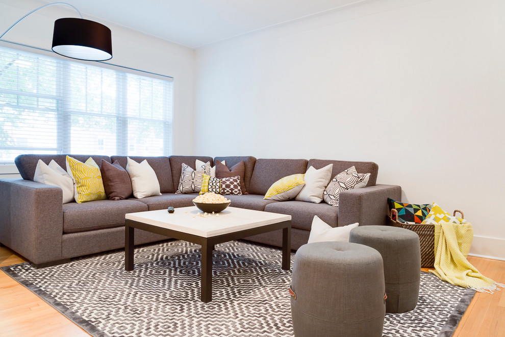 Imagen de sala de estar abierta bohemia de tamaño medio sin chimenea con paredes blancas, suelo de madera clara y pared multimedia
