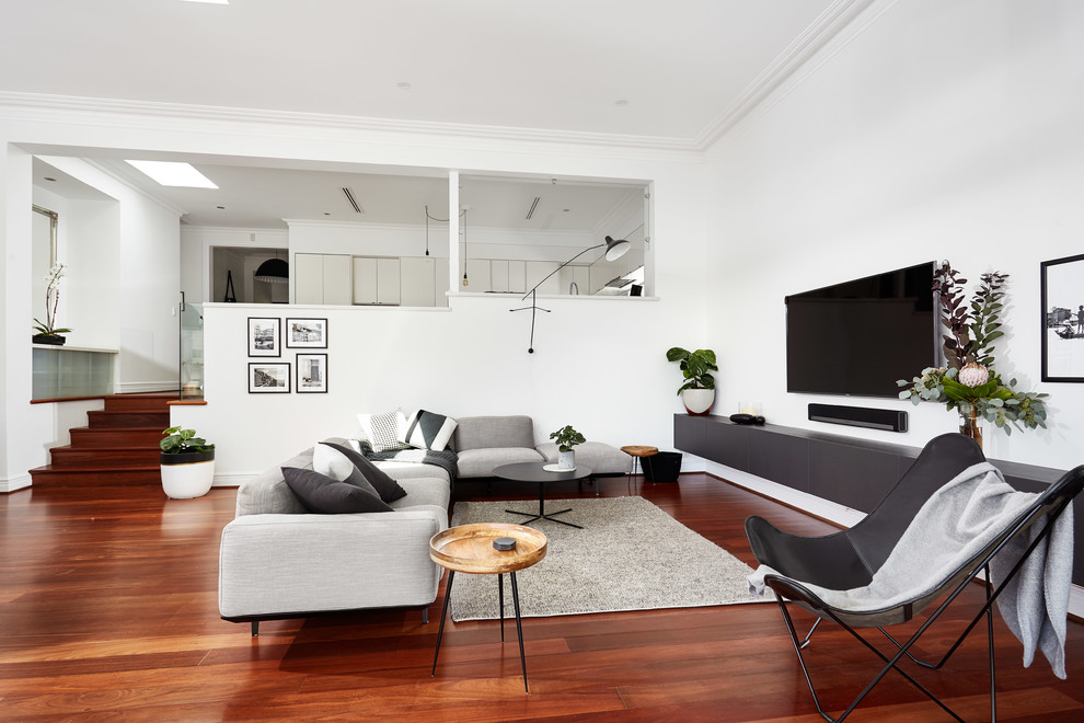 Diseño de sala de estar actual de tamaño medio sin chimenea con paredes blancas, suelo de madera en tonos medios, televisor colgado en la pared y suelo rojo