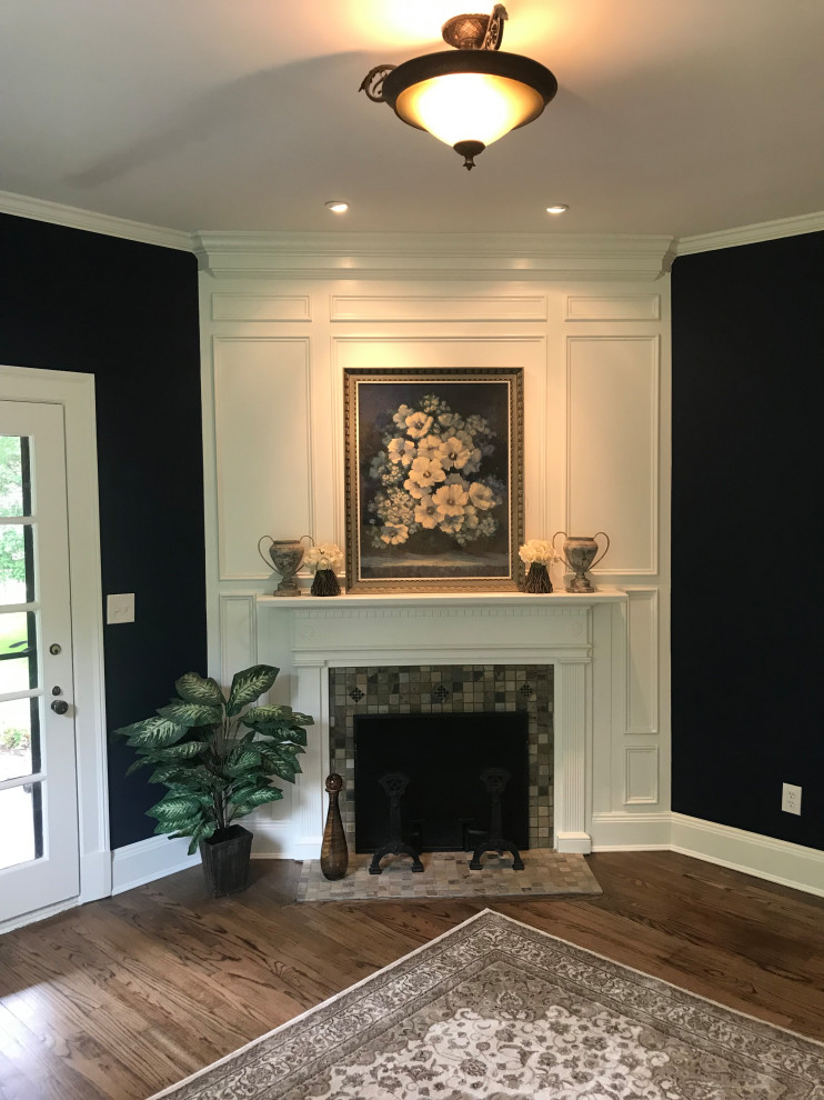 Imagen de sala de estar con biblioteca cerrada tradicional con paredes azules, suelo de madera oscura, chimenea de esquina, marco de chimenea de madera y suelo marrón