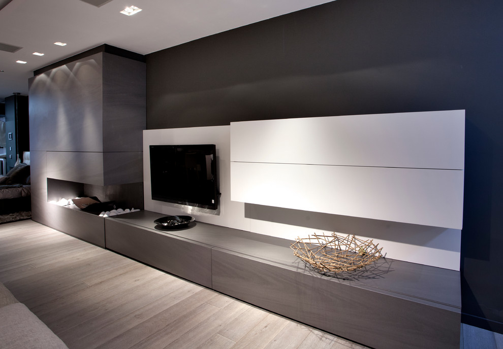 Ejemplo de sala de estar abierta moderna grande con paredes grises, suelo de madera clara, marco de chimenea de hormigón, televisor colgado en la pared y chimenea de esquina