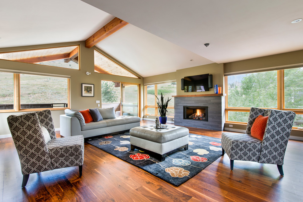 Offenes, Mittelgroßes Klassisches Wohnzimmer mit braunem Holzboden, gefliester Kaminumrandung, TV-Wand, Gaskamin und orangem Boden in Denver