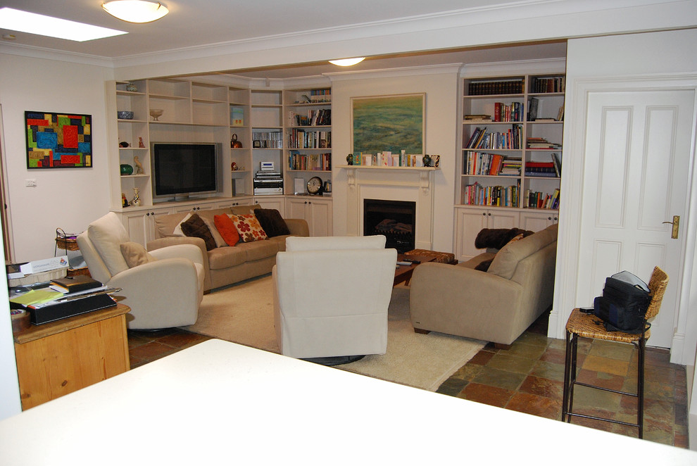 Cette image montre une salle de séjour traditionnelle de taille moyenne et ouverte avec une bibliothèque ou un coin lecture, un mur beige, un sol en ardoise, une cheminée standard, un manteau de cheminée en bois et un téléviseur indépendant.