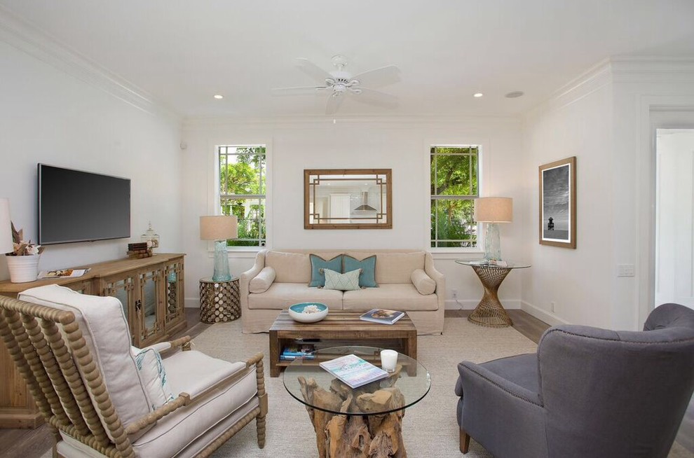 Foto de sala de estar abierta costera grande sin chimenea con paredes blancas, suelo de madera clara y televisor colgado en la pared