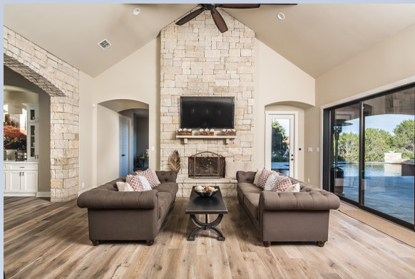 Imagen de sala de estar abierta tradicional renovada de tamaño medio con paredes beige, suelo de madera oscura, todas las chimeneas, marco de chimenea de piedra y televisor colgado en la pared
