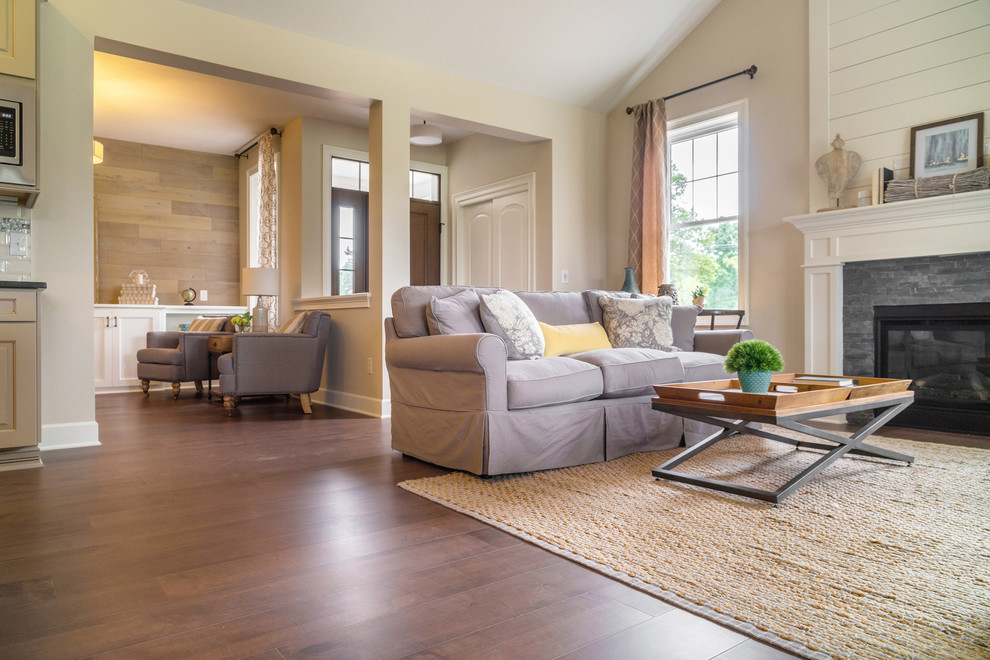 Imagen de sala de estar costera con suelo de madera oscura, marco de chimenea de piedra y suelo marrón