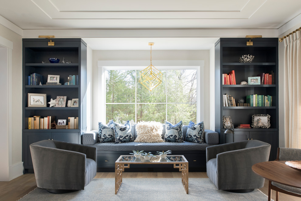 Diseño de sala de estar con biblioteca campestre sin chimenea con paredes beige y suelo de madera clara