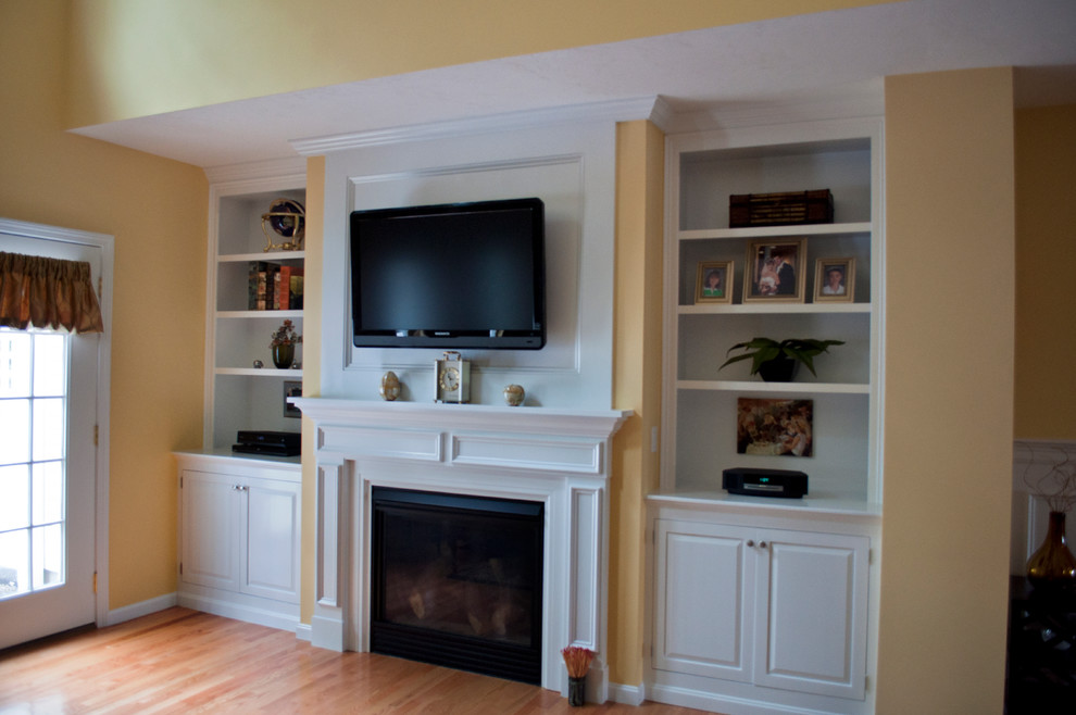 Large elegant light wood floor family room photo in Boston with yellow walls, a standard fireplace, a wood fireplace surround and a wall-mounted tv