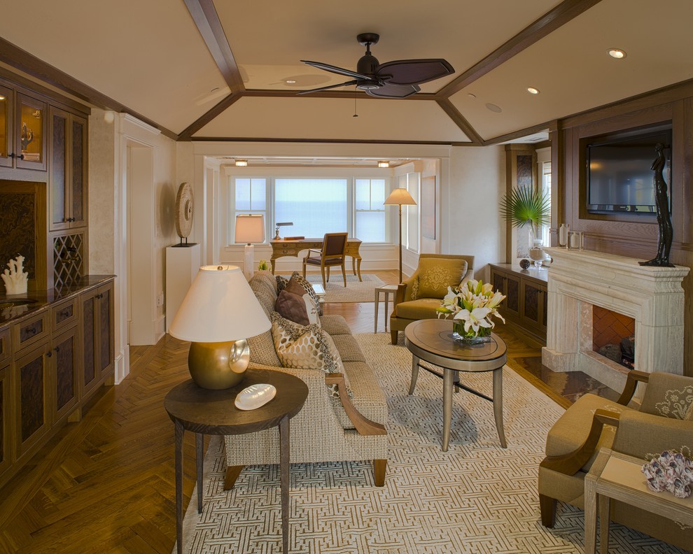 Imagen de sala de estar actual con paredes beige, suelo de madera en tonos medios, todas las chimeneas, marco de chimenea de piedra, televisor colgado en la pared y alfombra