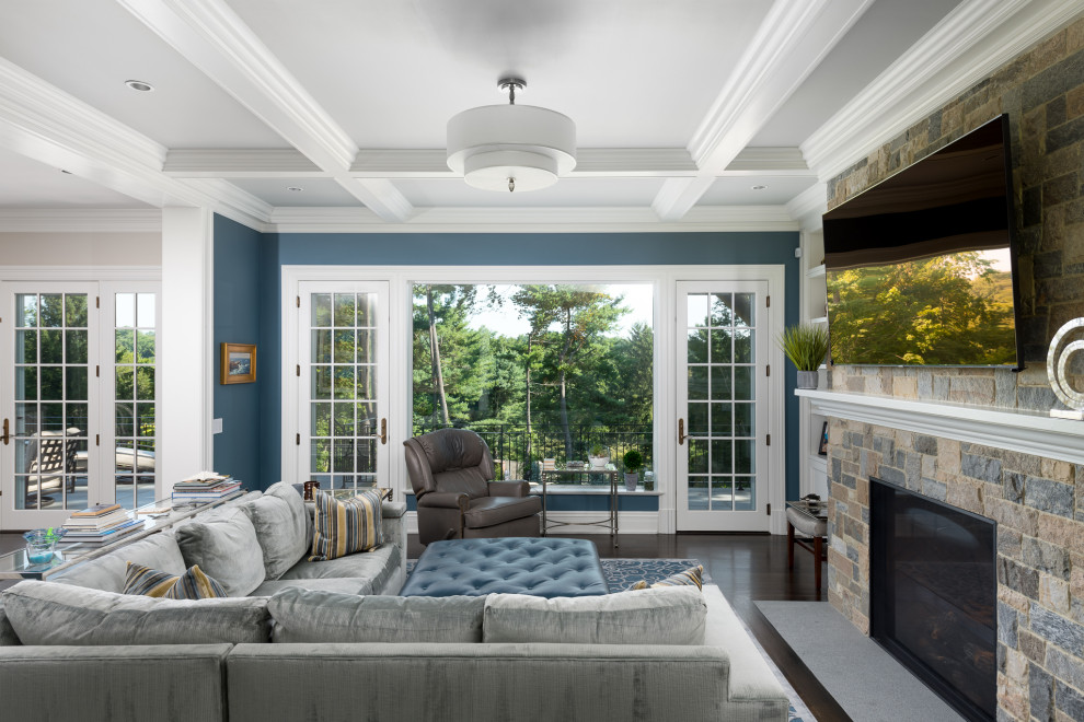 Diseño de sala de estar abierta tradicional con paredes azules, suelo de madera oscura, todas las chimeneas, marco de chimenea de piedra y televisor colgado en la pared