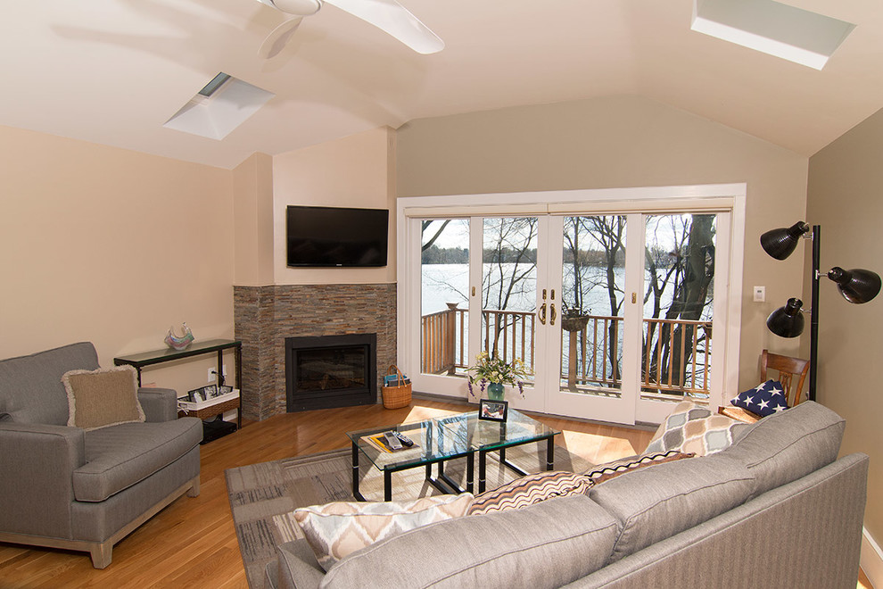 Mittelgroßes, Abgetrenntes Modernes Wohnzimmer mit beiger Wandfarbe, hellem Holzboden, Kaminumrandung aus Stein, TV-Wand und Eckkamin in Boston