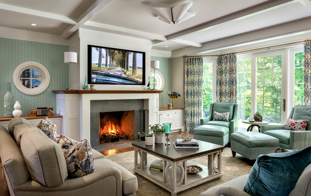 Immagine di un soggiorno stile marinaro con pareti verdi, camino classico, cornice del camino in cemento e TV a parete