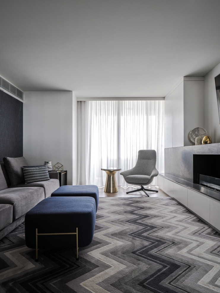 Imagen de sala de estar abierta actual grande con paredes grises, suelo de madera clara, chimenea lineal, marco de chimenea de piedra y suelo beige