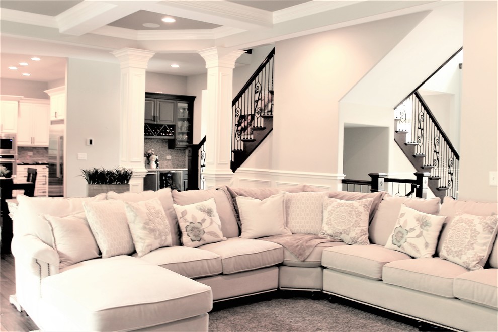 Modelo de sala de estar abierta clásica de tamaño medio sin chimenea y televisor con paredes beige, suelo de madera oscura y suelo marrón