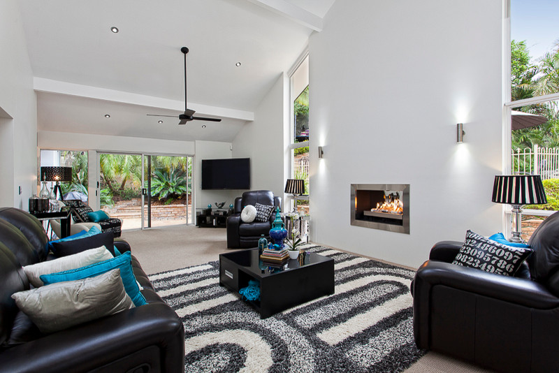 Geräumiges, Abgetrenntes Modernes Wohnzimmer mit weißer Wandfarbe, Teppichboden, Kamin, Kaminumrandung aus Metall und Eck-TV in Brisbane