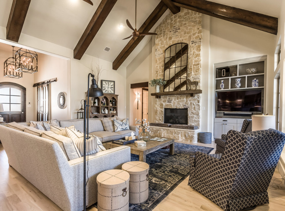 Design ideas for a large modern open plan games room in Dallas with white walls, light hardwood flooring, a standard fireplace, a stone fireplace surround, a wall mounted tv, brown floors and exposed beams.